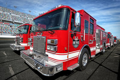 A wide-angle, close up shot of Pierce fire trucks on the Daytona International Speedway racetrack.