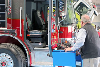 A Pierce employee is performing a final product evaluation by inspecting this fire truck with great detail using a documentation system on his tablet.