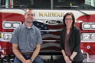 Two Pierce former interns, now full-time employees stand in front of a Pierce fire truck. Zach on left and Sheena on the right. 