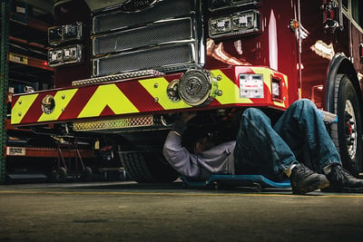 A Pierce Master Technician works under the fire truck cab