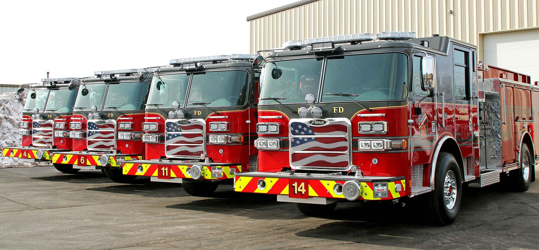 Four standardized Pierce fire trucks all part of the same fleet lined up in a row.
