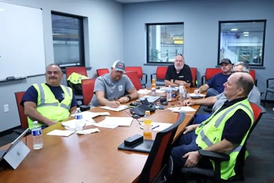 A fire department committee reviews plans during a pre-construction meeting around a conference table.