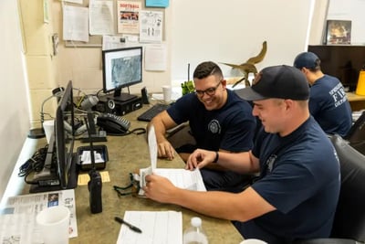 Firefighters reviewing purchase order specifications on a clipboard in the station office.
