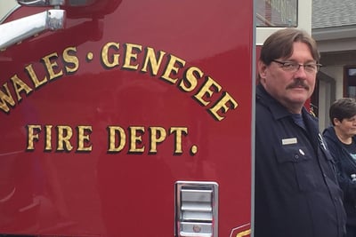 A firefighter with the Wales-Genesee Fire Department stands next to a fire apparatus. 