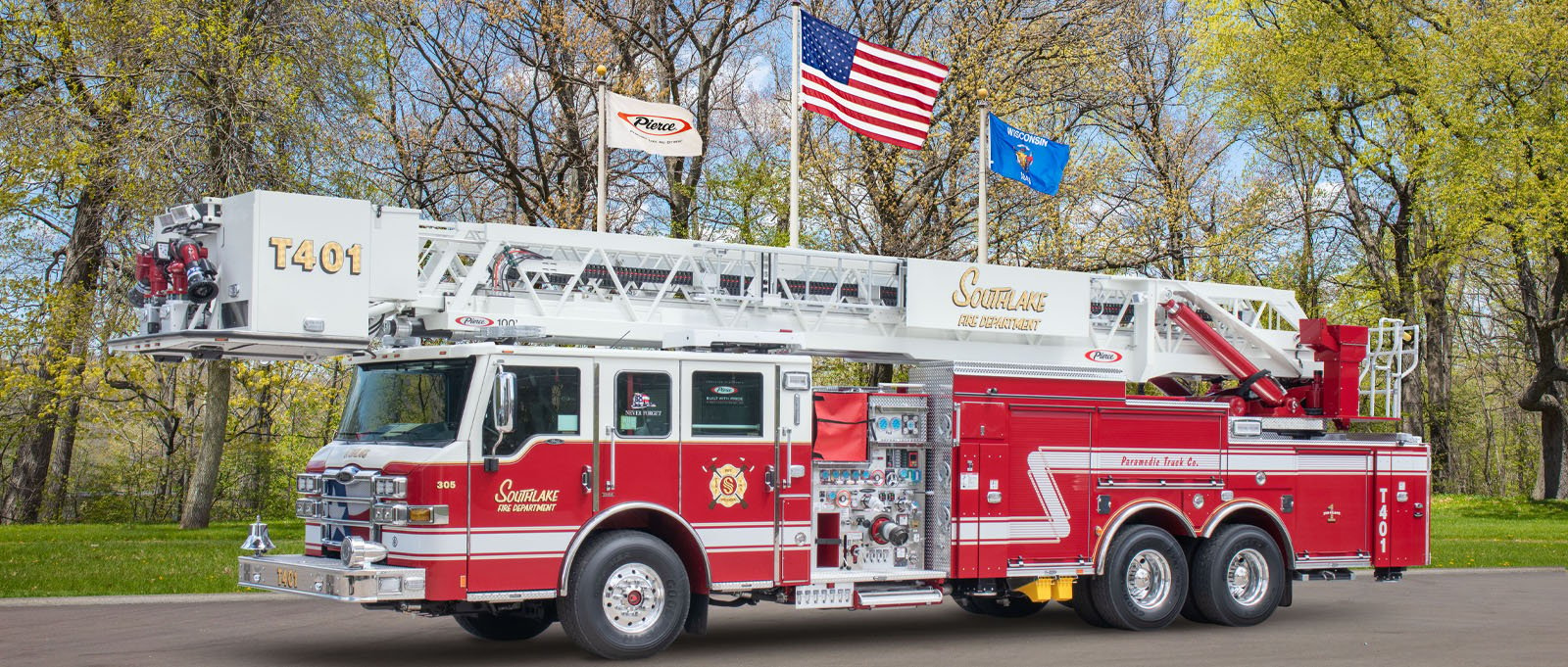 The Southlake Department of Public Safety aerial fire truck is pictured parked in front of three flags and green trees at Pierce Manufacturing. 