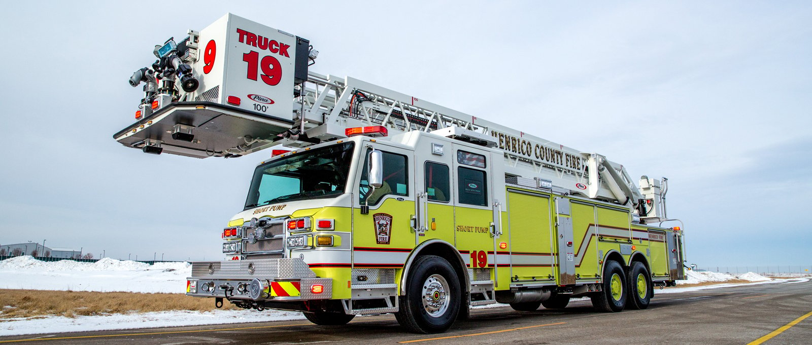 A yellow fire truck is parked with the rear in the foreground to show the independent rear suspension system graphic that overlays the image. 