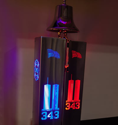 An image of the donated victory bell at night shows red and blue light illuminating the Twin Towers and the number 343 for the number of firefighters who died on Sept. 11, 2001.