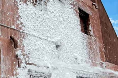 A close up of a brick building that has class A foam sprayed over most of the building’s area shown. 