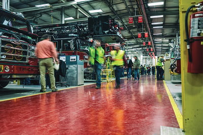 A busy fire truck manufacturing facility is buzzing with experienced team members working on fire apparatus and fulfilling customer needs