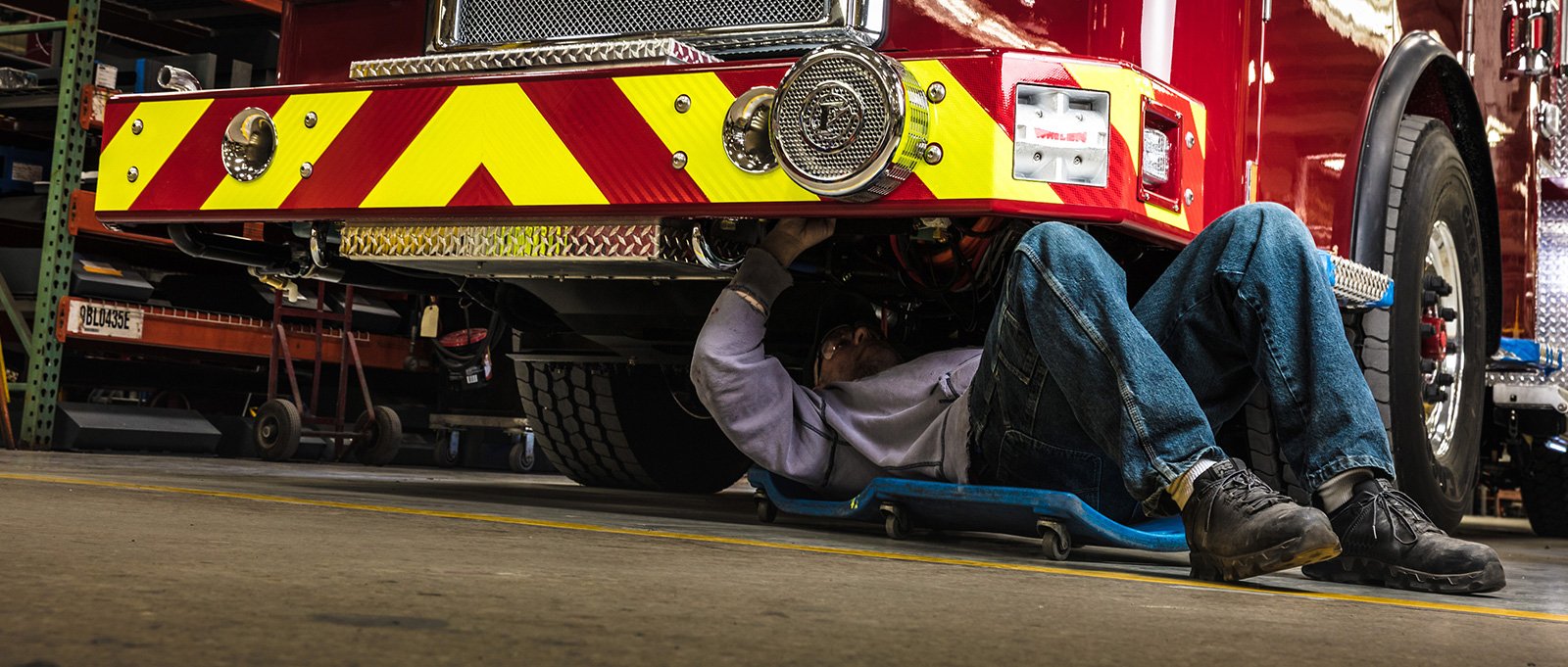 Manufacturing employees at Pierce doing maintenance under the Pierce fire truck. Employees have real-life experience working and responding with fire apparatus in the field