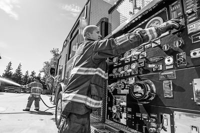 A firefighter manages the controls of a fire apparatus pump panel.