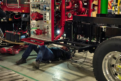 A Pierce employee lays beneath the fire truck cab and completes tasks associated with the final assembly process. 