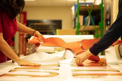 Two Pierce team members work together to remove custom fire truck graphics from the adhesive material to prepare them for application. 