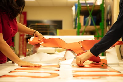 Two Pierce team members work together to remove custom fire truck graphics from the adhesive material to prepare them for application. 