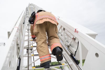 A firefighter climbs a ladder raised in the vertical position. 