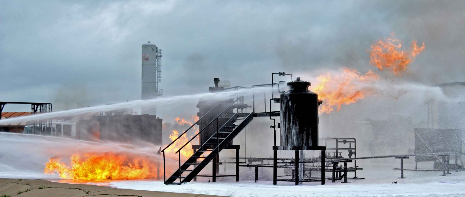 Industrial fire being actively put out and suppressed by a fire fighting foam system.