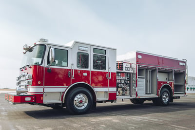 A fully equipped heavy-duty rescue pumper sits on a black tarmac. 