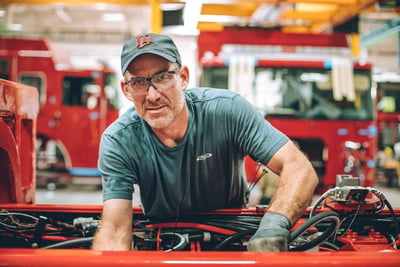 A close up image of a Pierce team member looking up as he works on the fire truck manufacturing floor. 