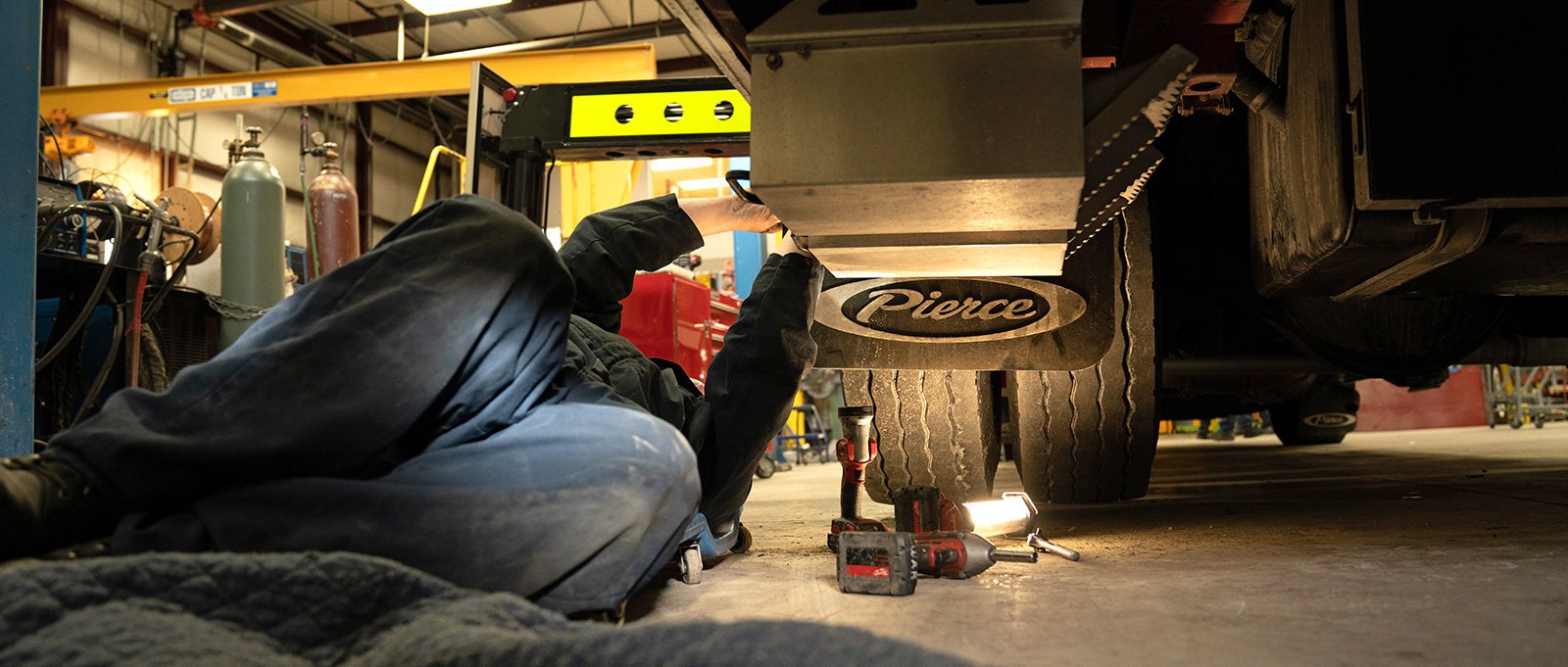 Pierce fire truck mechanic on the floor performing fire truck maintenance.