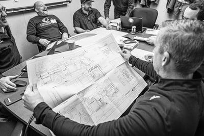 pierce-firetruck-dealersMembers of a fire department sit around a conference table with a fire apparatus dealer reviewing firetruck blueprints.