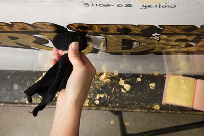 An overhead image of the hand-burling application process of gold leaf fire truck graphics to Pierce fire trucks.