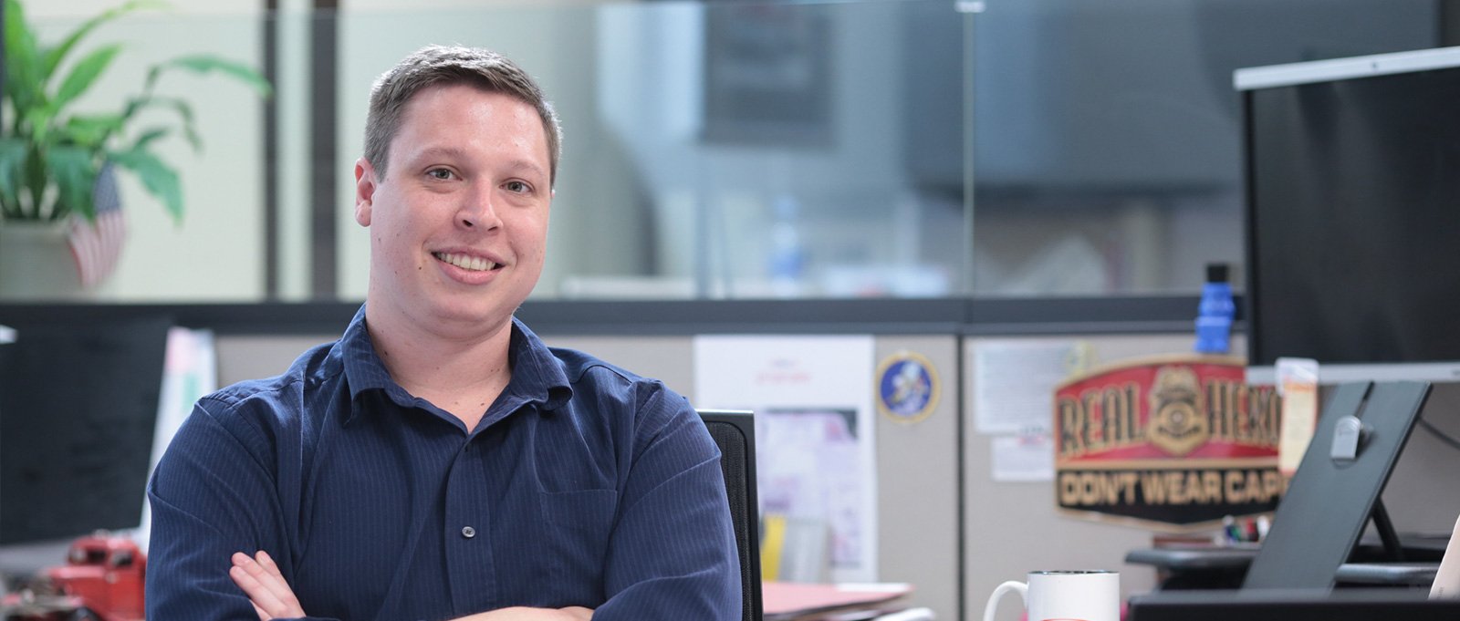 Pierce Manufacturing jobs are available now. Pictured here is an employee working for Pierce Manufacturing sitting at his desk, smiling at the camera. At Pierce, you’re part of a family.  