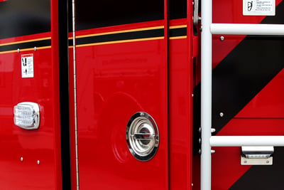 : A rescue pumper fire truck is positioned outdoors with hinged doors open to show the compartment interiors.