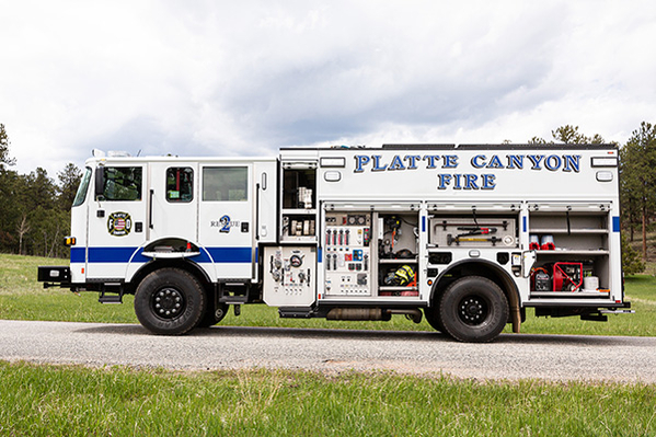 Drivers side of pumper fire truck doors open showing compartments and firefighter equipment