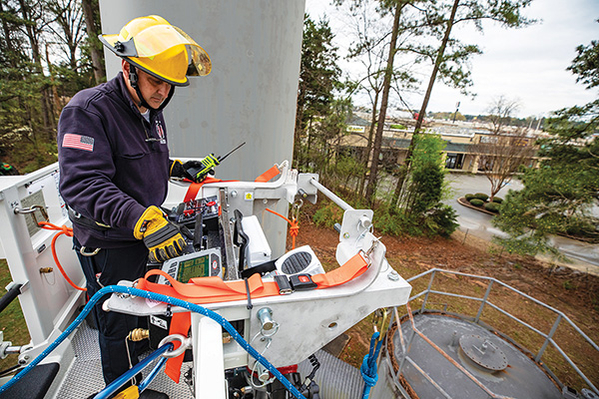 Firefighter standing in aerial platform fire truck basket responding to a rescue call