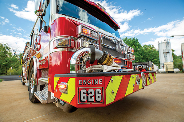 Front bumper of fire truck parked on concrete on a partly cloudy day