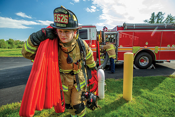 Firefighter carrying hose from pumper fire truck
