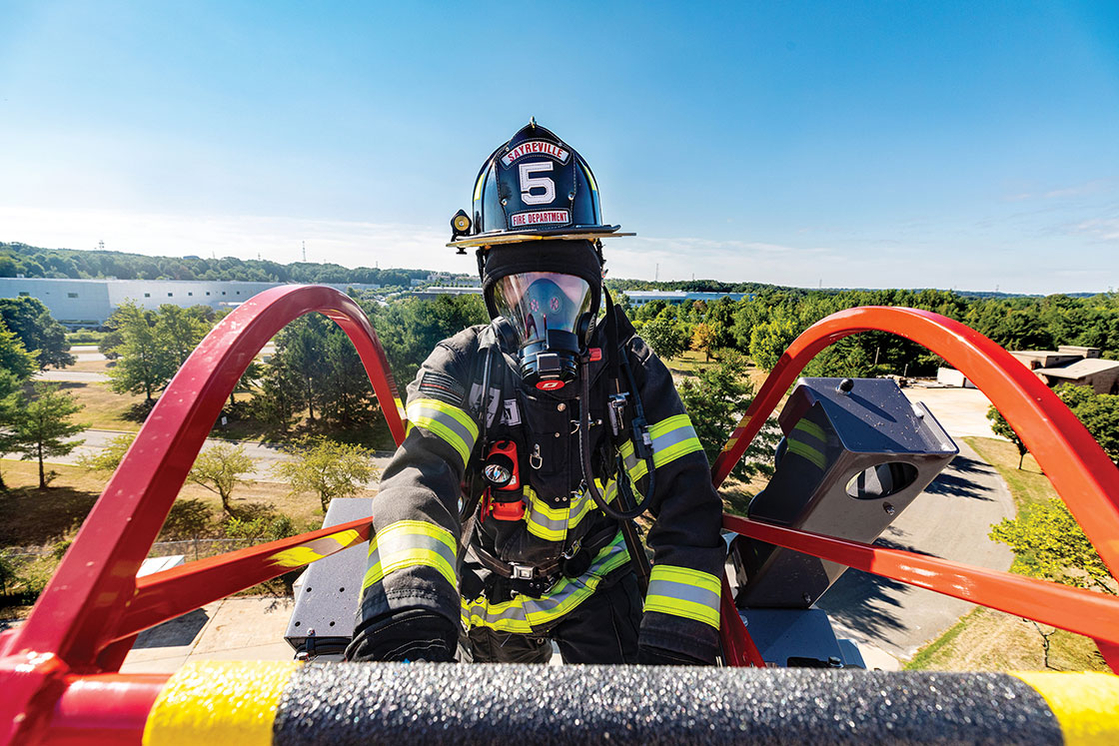 Firefigher climbing up to the tip of an aerial ladder fire truck