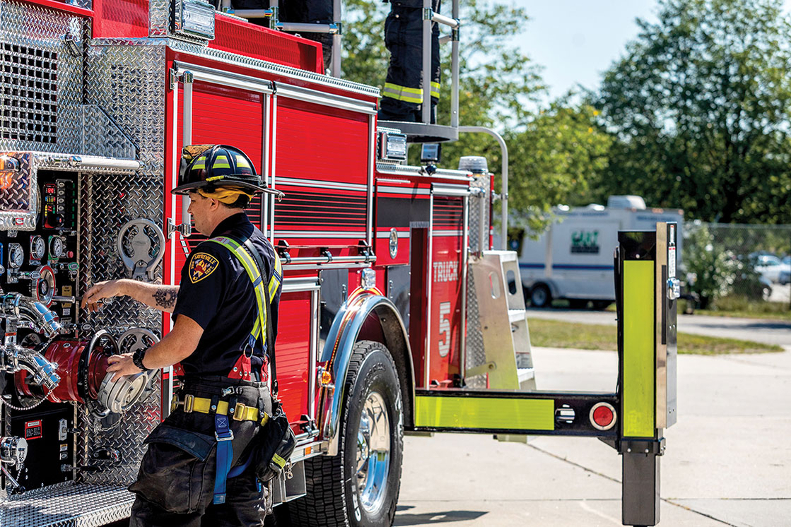 Firefighter operating pump panel on aerial fire truck