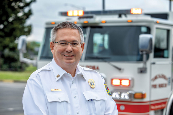 Tuscaloosa Fire Chief in front of new pumper fire truck with emergency lights flashing