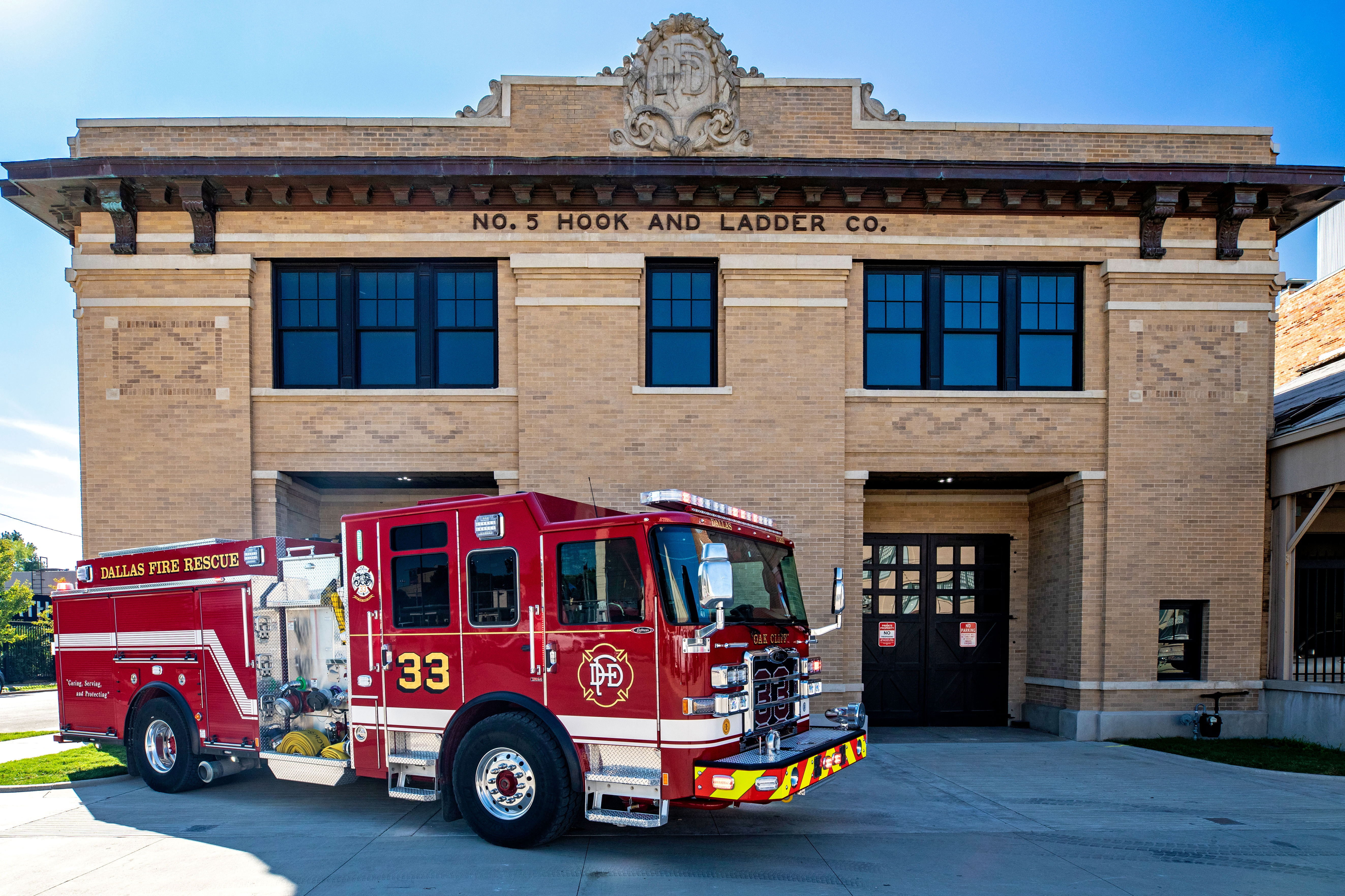 Custom pumper fire apparatus parked outside of historical fire station