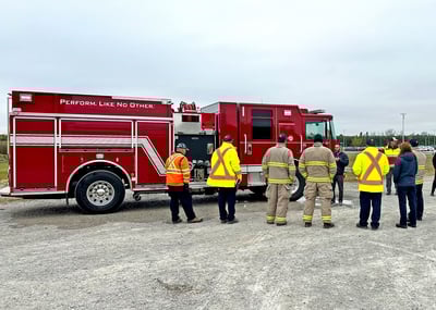 A red Pierce fire truck with a group of fire fighters standing around it.