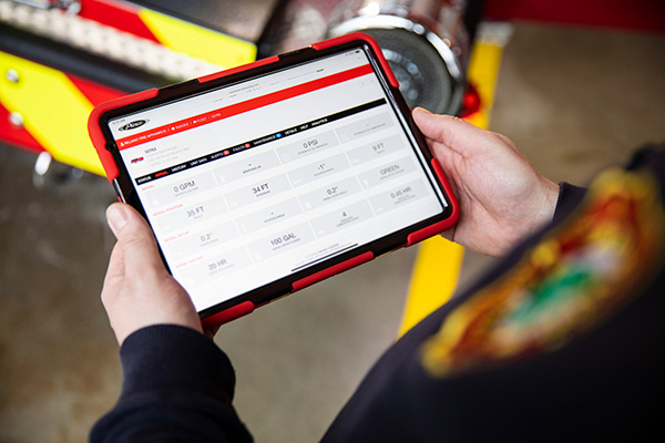 Fire Chief standing near a Fire Truck holding a tablet showing Fire Truck Data using the ClearSky™ web-portal.