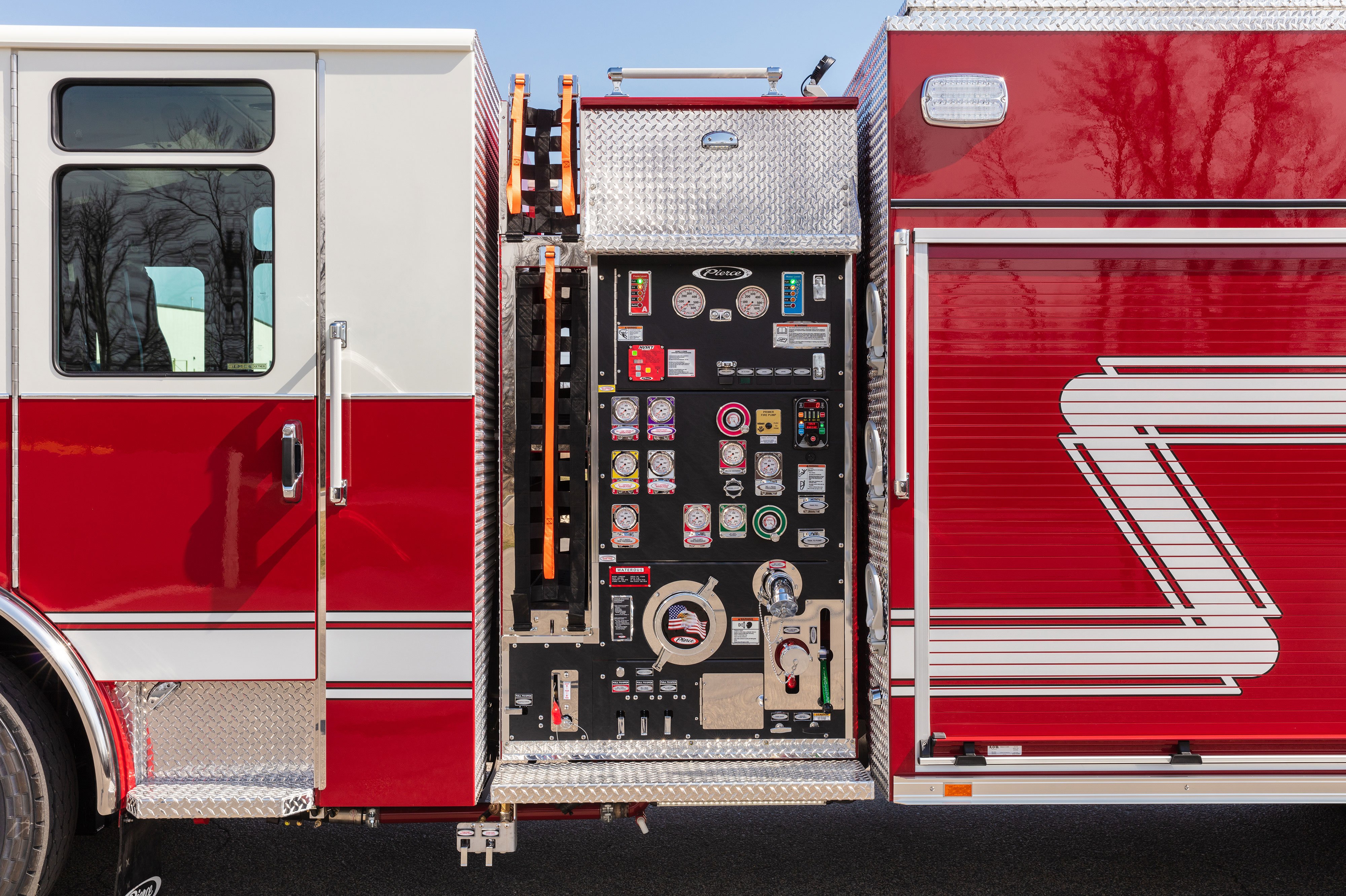 Side control pump with side mount speedlays on the driver’s side of a Pierce Fire Truck parked outside on a sunny day. 