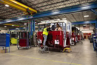 A red fire truck getting it's frame, cab and chassis assembled during the manufacturing process.
