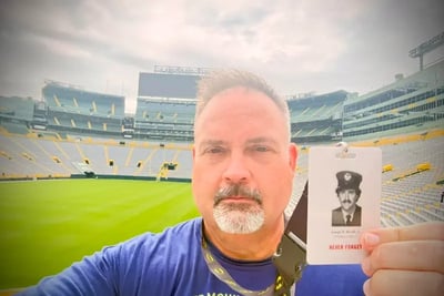 A man holds a 9/11 memorial badge for firefighter Joseph R. Rivelli, Jr. at Lambeau Field.