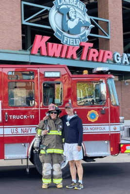 A firefighter and supporter pose in front of a U.S. Navy fire truck at the Lambeau Field stair climb.