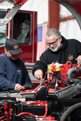 Two service technicians from Golden State Fire working on the engine of a fire apparatus.
