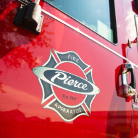 A closeup image of a red fire truck with black Pierce logo.