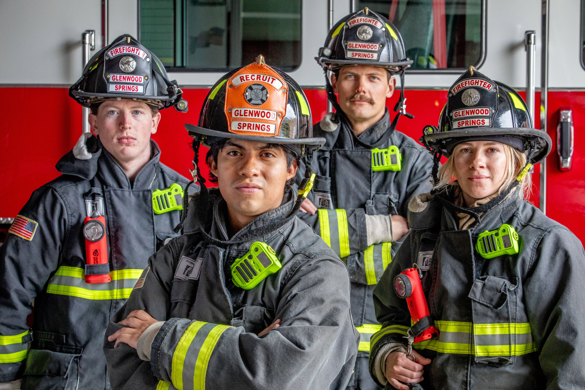 Four Glenwood Springs firefighters in full turnout gear standing in front of a red fire engine.