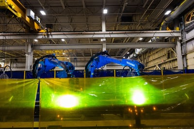 Two automated rail welding arms manufacturing an aerial ladder for a fire truck in a modern manufacturing facility.