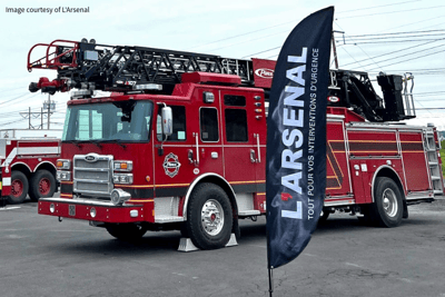 A red Pierce fire truck with black flag reading L'Arsenal in front of it.