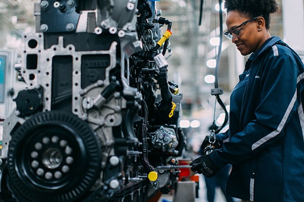 A woman servicing a PACCAR MX-13 Engine for a Pierce Fire Truck in a warehouse. 