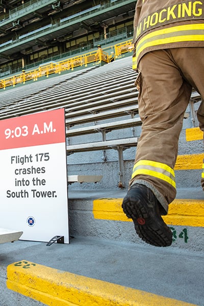 A Firefighter in firefighting gear climbing the stairs at Lambeau Field at the Pierce 9/11 Memorial Stair Climb event.