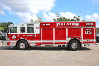 A red and white fire truck from Palatine, Illinois sitting on pavement with power lines and blue skies in the background.
