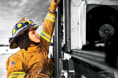 Woman firefighter reaching up on a Pierce fire truck